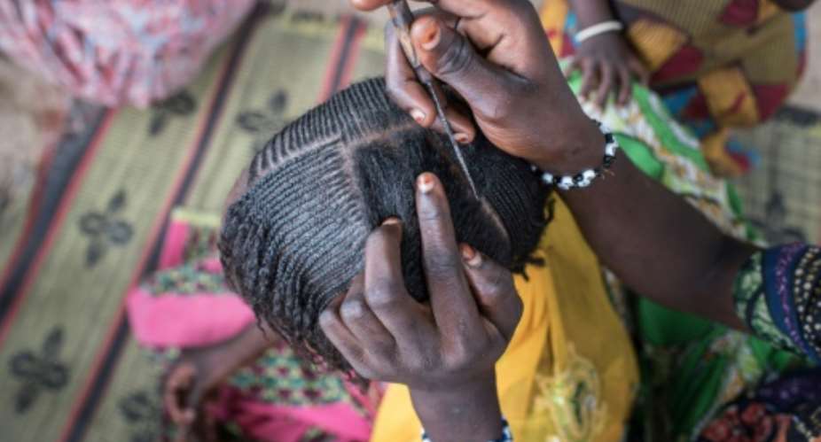 A woman braids a girl's hair at a camp for the internally displaced in northeast Nigeria, where rights groups say women and girls are at serious risk of sexual abuse and rape.  By STEFAN HEUNIS AFPFile