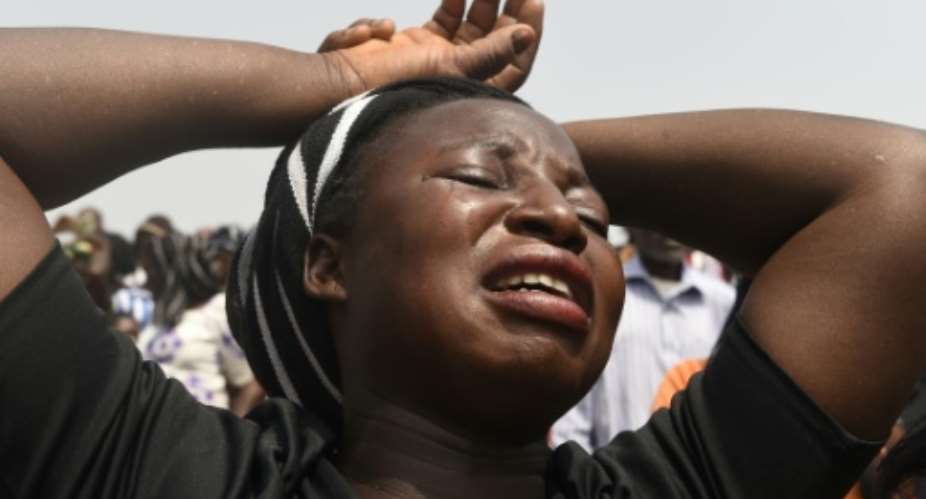 A woman bursts into tears as the casket of her father is brought into Ibrahim Babangida Square during a funeral service for people killed during clashes between cattle herders and farmers.  By PIUS UTOMI EKPEI AFP