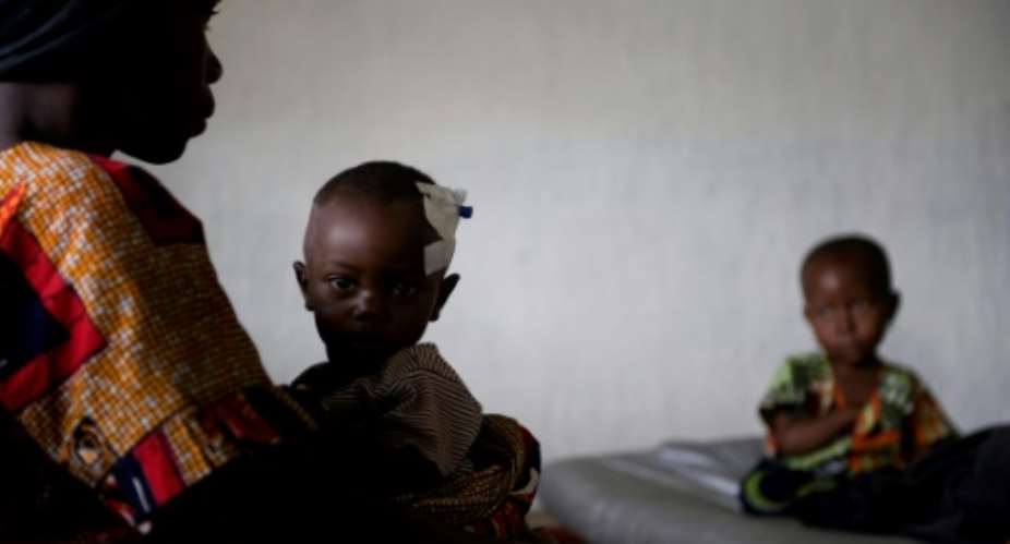 A woman cares for her child as cholera victims sit on beds at a provisional French non-governmental organization Medecins Sans Frontieres clinic in the Democratic Republic of Congo in 2008.  By WALTER ASTRADA AFPFile