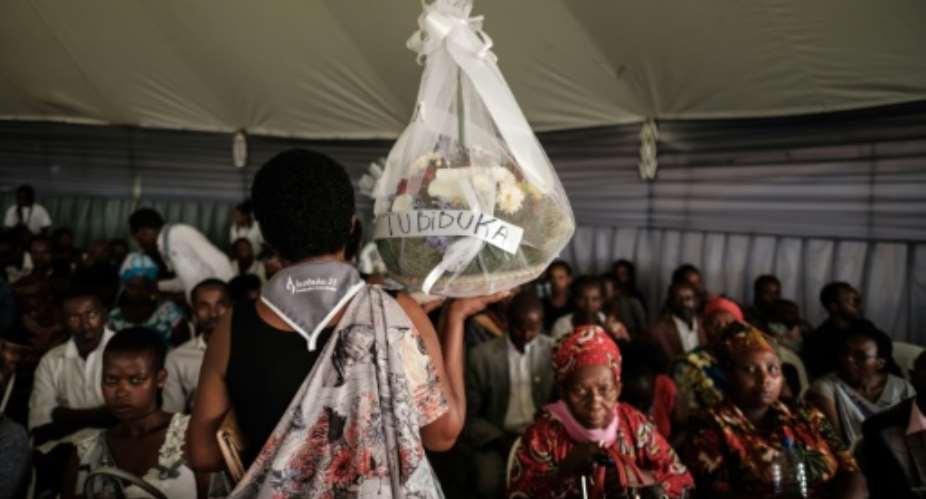 A woman carries flowers to offer before the mass funeral to bury 81 coffins containing newly discoverd remains of 84,437 victims of the 1994 genocide in the mass grave at the Nyanza Genocide Memorial, suburb of the capital Kigali, on May 4, 2019. The remains of nearly 85,000 people murdered in Rwanda's genocide were laid to rest on May 4 in a sombre ceremony in Kigali, a quarter of a century after the slaughter.  By Yasuyoshi CHIBA AFP
