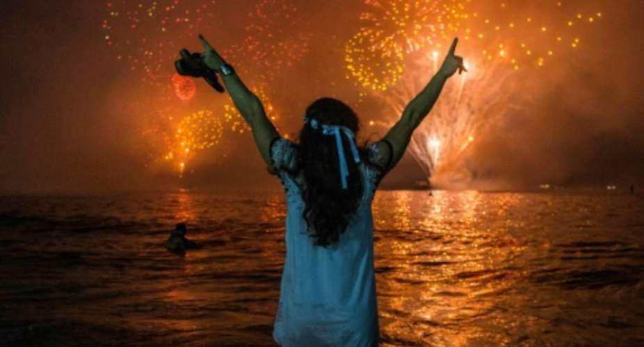 A woman celebrates as she watches the traditional New Year's fireworks at Copacabana Beach in Rio de Janeiro, Brazil, with an estimated three million revelers.  By DANIEL RAMALHO AFP