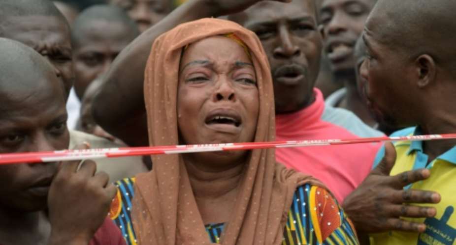 A woman cries at the scene of a deadly four-storey building collapse in Lagos on July 26, 2017.  By PIUS UTOMI EKPEI AFP