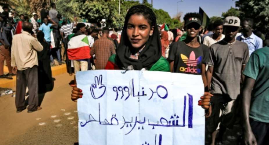 A woman holds up a sign reading in Arabic: The people demand retribution for the martyrs, during a demonstration in the centre of Sudan's capital.  By ASHRAF SHAZLY AFP