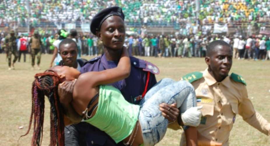 A woman injured during the stampede is carried away by a policeman.  By Saidu BAH AFP