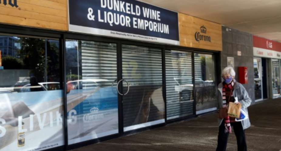 A woman walks past a closed liquor shop in Johannesburg in July 2020.  By Michele Spatari AFPFile
