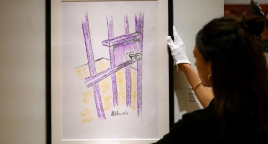 A worker at Bonhams auction house holds a sketch by Nelson Mandela -- The Cell Door, Robben Island -- in New York, where it will go up for sale on May 2, 2019.  By Johannes EISELE AFP