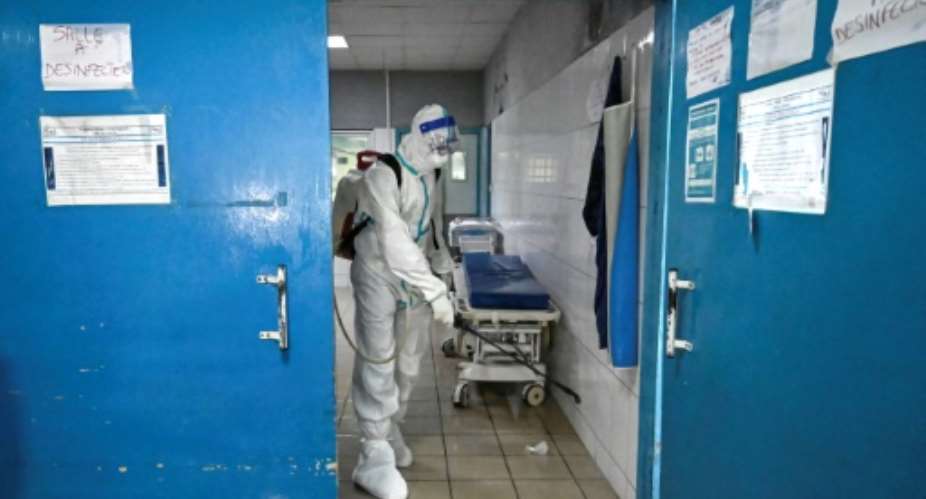 A worker at the hospital in Cocody, where the Ebola patient was first treated, sprays disinfectant as a precaution.  By Sia KAMBOU AFP