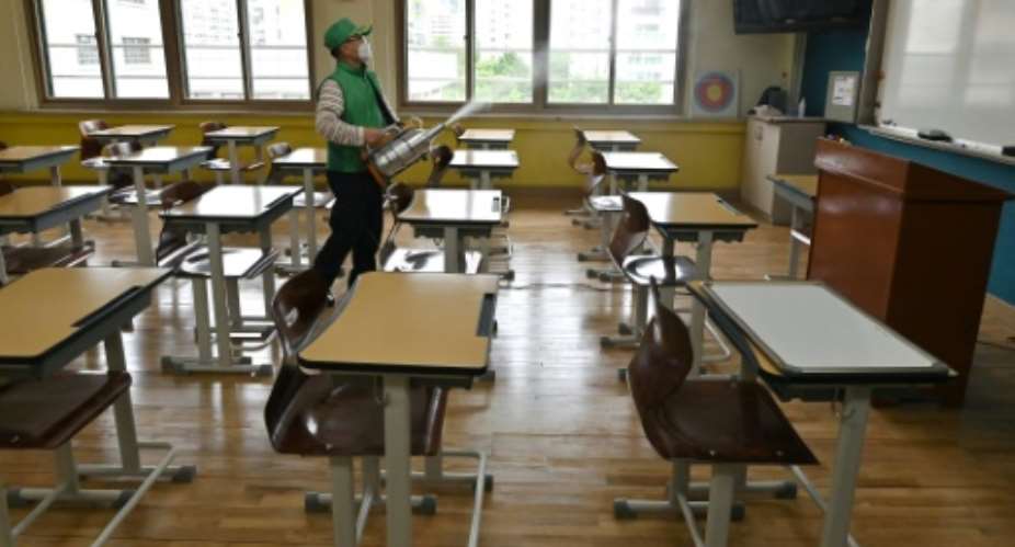 A worker sprays disinfectant in a classroom at a high school in Seoul.  By Jung Yeon-je AFP