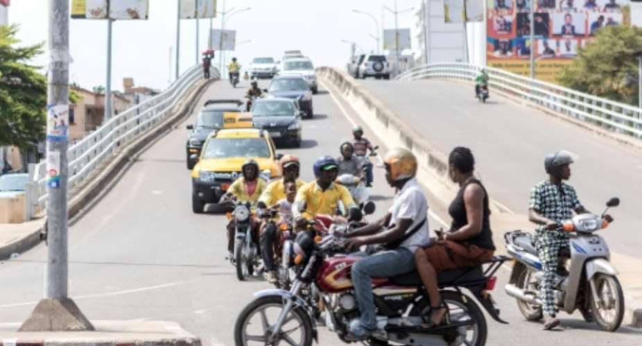 A yellow Benin-Taxi car is seen among several motorbike-taxis at a busy intersection in Cotonou.  By YANICK FOLLY AFP