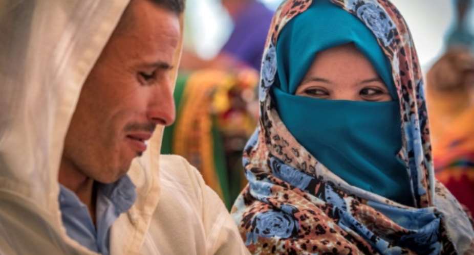 A young Amazigh couple smile at each other as they wait for their turn at a group wedding in Morocco's Atlas mountains.  By FADEL SENNA AFP