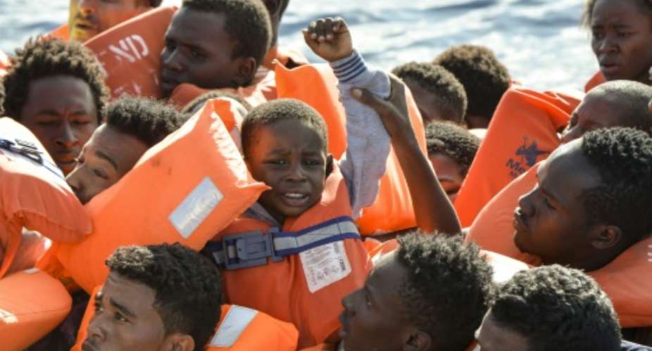 A young boy is seen among the migrants and refugees seated on a rubber boat and waiting to be rescued by the Topaz Responder, a rescue ship run by Maltese NGO Moas and the Italian Red Cross, off the Libyan coast.  By ANDREAS SOLARO AFPFile