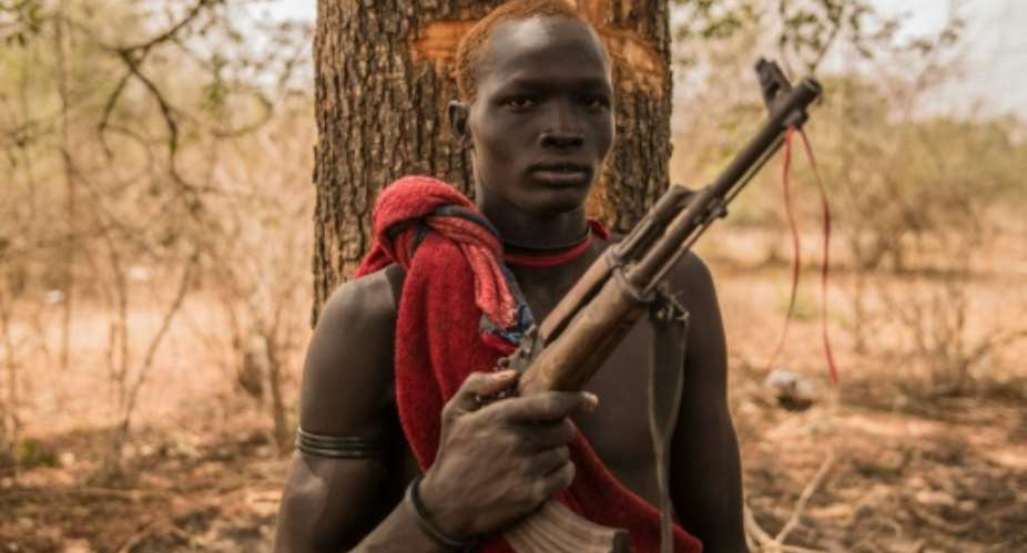 A young herdsman from the Dinka tribe poses with a semi-automatic weapon. Guns are rife in rural South Sudan, for self-protection or defence against cattle raiders.  By Stefanie GLINSKI AFP