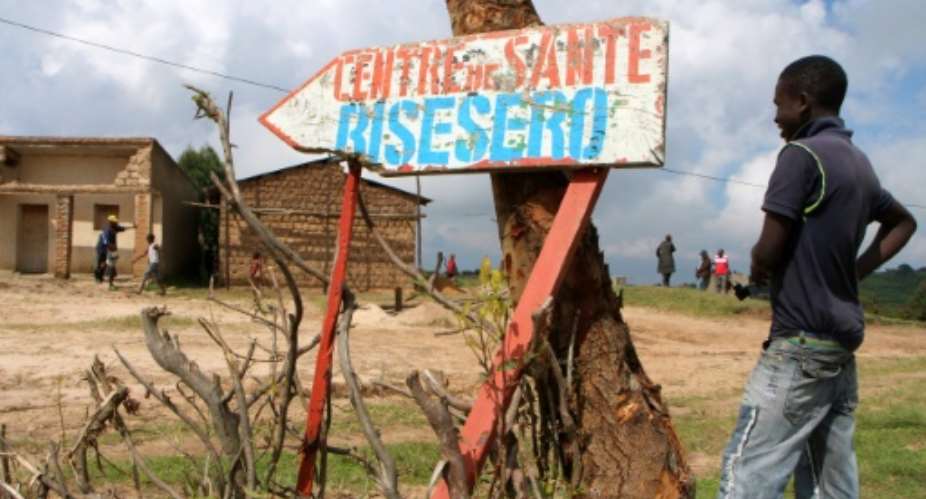 A young man stands next to a sign for a health center in Bisesero, western Rwanda, where survivors say French soldiers had promised to rescue terrified Tutsis hiding in the hills at the height of the killing in June 1994.  By STEPHANIE AGLIETTI, STEPHANIE AGLIETTI AFPFile