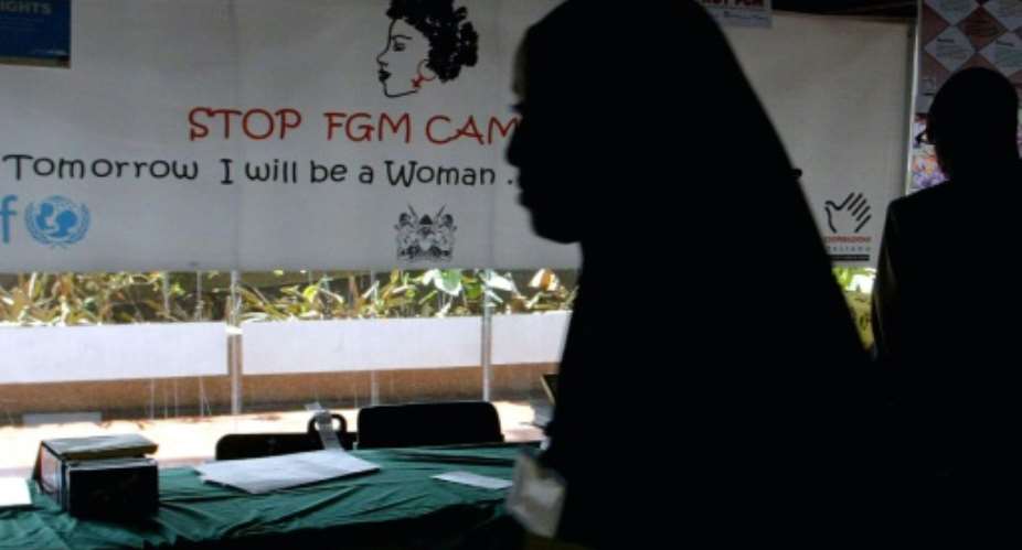 A young woman walks past a banner against female genital mutilation.  By SIMON MAINA AFPFile