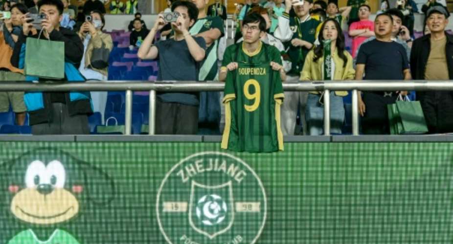 A Zhejiang FC fan holds up a shirt of Aaron Boupendza, the Gabon international footballer who was found dead earlier on Wednesday after an apparent fall from the 11th floor of a building.  By - (AFP)
