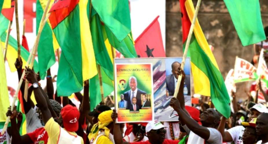 Activists of the African Party for the Independence of Guinea and Cape Verde PAIGC hold a picture of Guinea-Bissau's party leader Domingos Simoes Pereira during a rally in March 2019.  By SEYLLOU AFPFile