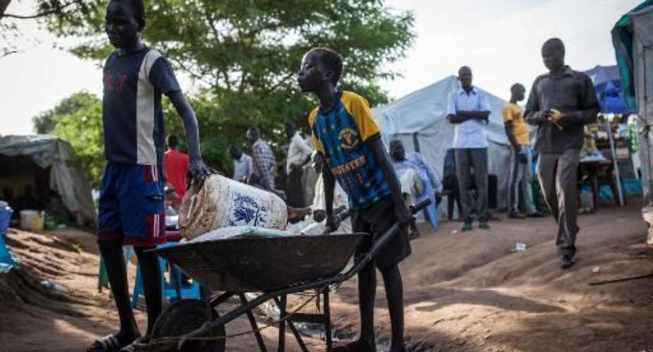 Boys push a wheelbarrow with goods at the Tomping Internally Displaced Persons (IDP) camp in Juba on July 2, 2014.  By Nichole Sobecki (AFP/File)