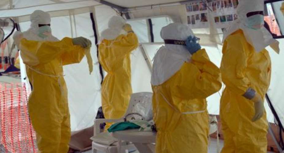 Liberian health workers don full protection outfits at a Medecins Sans Frontieres Ebola treatment center in Monrovia, on October 18, 2014.  By Zoom Dosso AFPFile