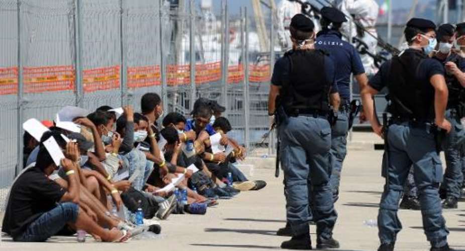 Immigrants wait after disembarking from an Italian military ship on August 11, 2014 in the port of Reggio Calabria, southern Italy, following Mare Nostrum rescue operations at sea.  By Giovanni Isolino AFPFile