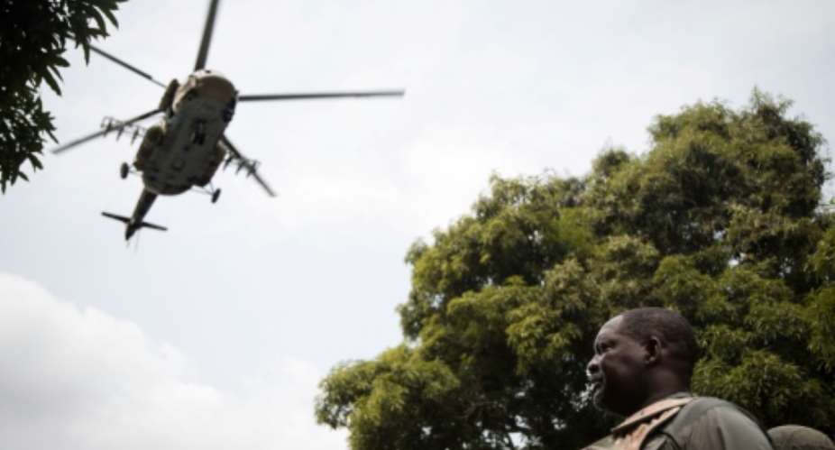 Air support: Prime Minister Firmin Ngrebada salutes the troops on January 10 as a Russian military helicopter flies overhead.  By FLORENT VERGNES AFP