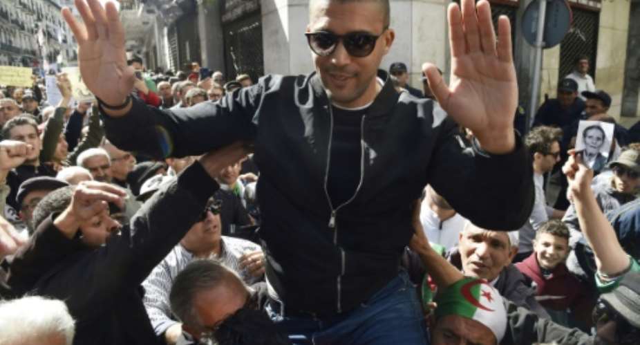 Algerian protesters carry journalist Khaled Drareni, who was arrested while covering an anti-government protest and was accused of inciting an unarmed gathering and damaging national integrity, on their shoulders on March 6, 2020 in Algiers.  By RYAD KRAMDI AFPFile