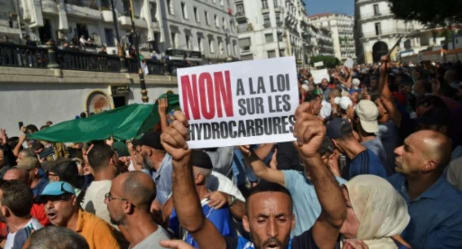 Algerian protesters chant anti-government slogans near the parliament building in Algiers on October 13, 2019 against the military's role in politics and a draft energy law.  By RYAD KRAMDI AFP