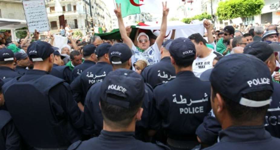 Algerian protesters face riot police during a demonstration in the capital Algiers in June.  By - AFP