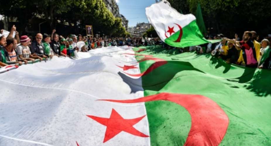Algerian protesters march with a giant national flag during a demonstration in the capital Algiers on May 31, 2019.  By RYAD KRAMDI AFPFile