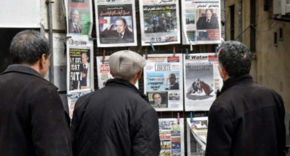 Algerians look at the headlines of newspapers at a kiosk in the capital Algiers on February 11, 2019.  By RYAD KRAMDI AFP