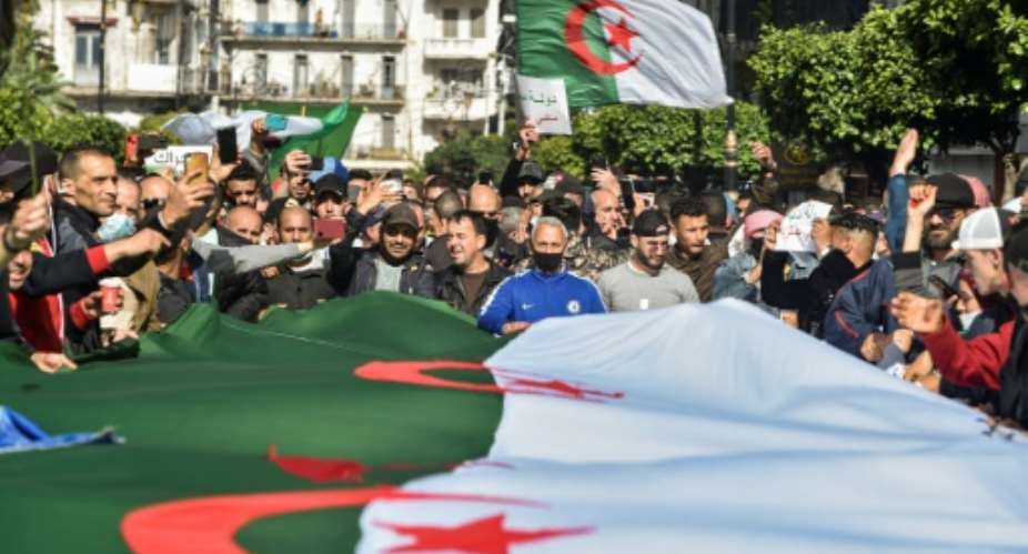 Algerians wave national flags during an anti-government protest in the capital Algiers on Friday.  By RYAD KRAMDI AFP