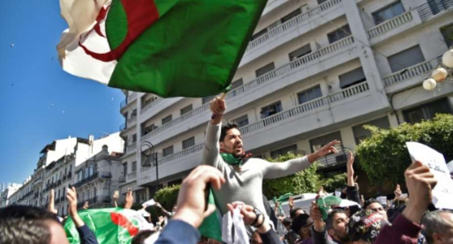 Algerians wave the national flag during a protest rally against ailing President Bouteflika's bid for a fifth term, in the capital Algiers on March 1, 2019.  By RYAD KRAMDI AFP