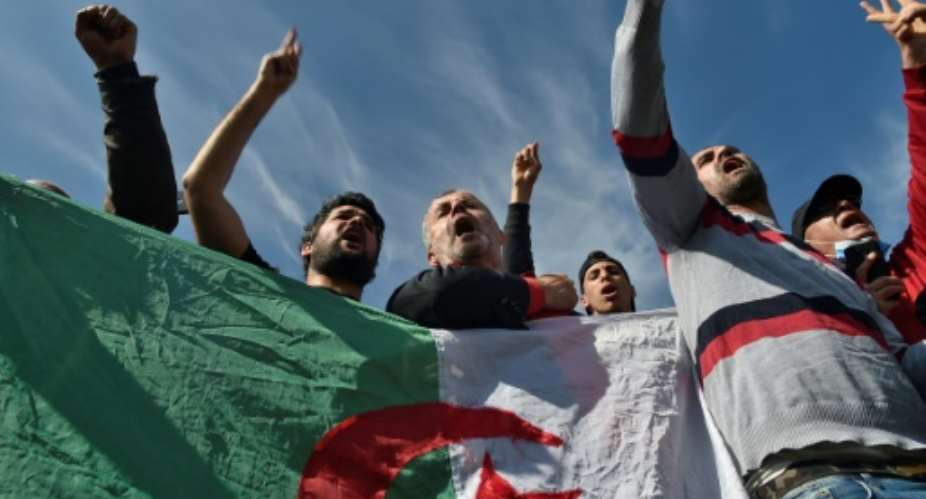 Algerians waving flags gathered outside the Kolea prison on Friday to await activists expected to be freed under a presidential pardon.  By RYAD KRAMDI AFP