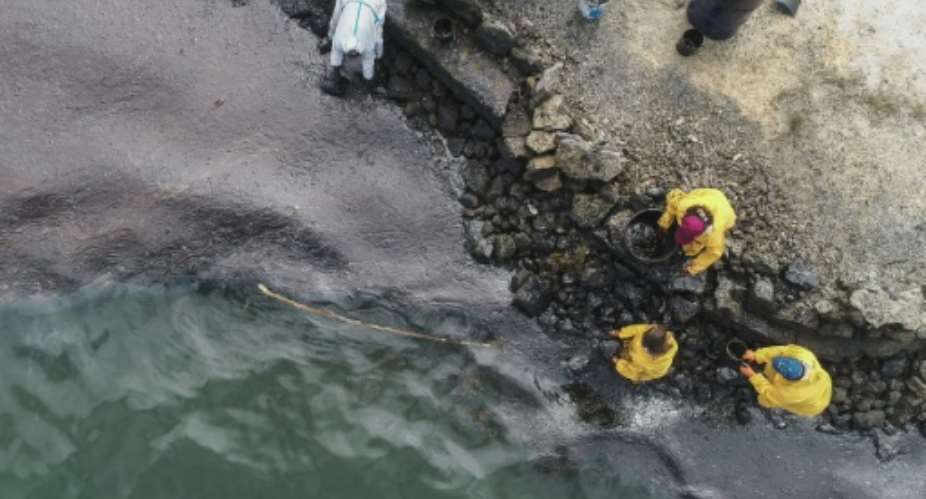 All-hands emergency: People scoop up oil at Bambous Virieux beach.  By - L'Express MauriceAFP