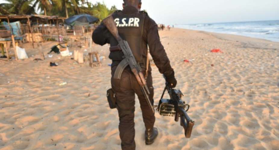 A soldier carries a machine gun as he walks on the beach resort of Grand-Bassam after gunmen went on a shooting rampage in three hotels, on March 13, 2016.  By Sia Kambou AFP