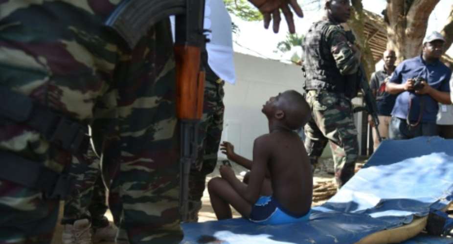 A wounded child is surrouned by Ivorian security forces after heavily armed gunmen opened fire on March 13, 2016 at a hotel in the Ivory Coast beach resort of Grand-Bassam.  By Sia Kambou AFP