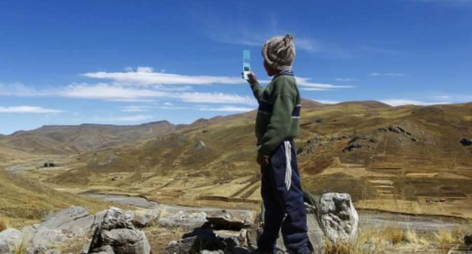 Alvaro Cabrera, 10, searches for a cellphone signal atop a hill near Manazo, Peru while trying to take part in a virtual class; the UN says Covid-19 and school closures have left millions of children worldwide unable to access distance education.  By Carlos MAMANI AFPFile
