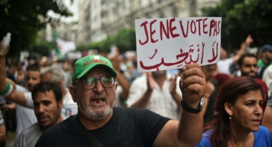 An Algerian protester holds a placard reading I won't vote during a demonstration against the ruling class in the capital Algiers on September 13, 2019, for the 30th consecutive Friday since the movement began.  By RYAD KRAMDI AFPFile