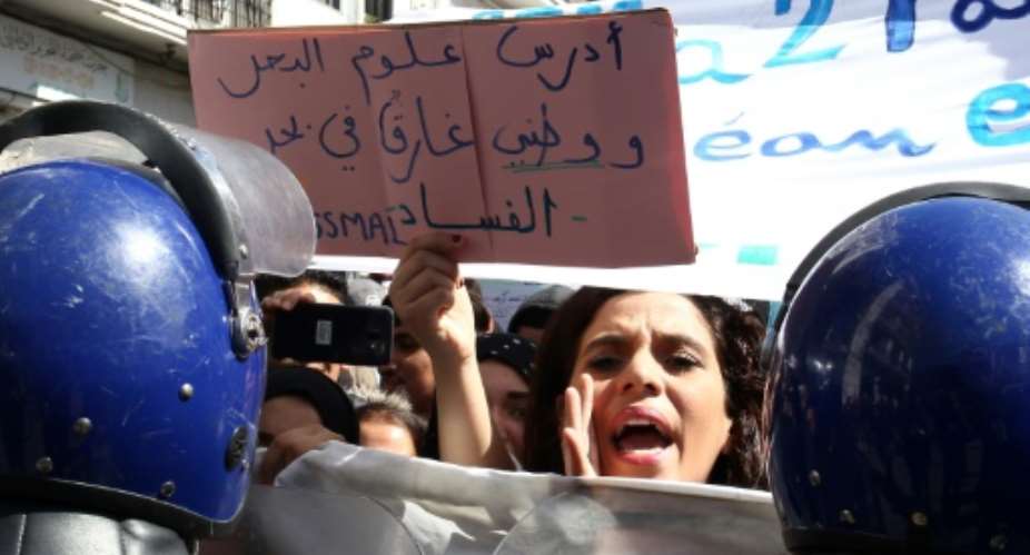 An Algerian protester holds sign that reads