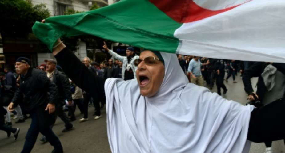 An Algerian woman waves a national flag during an  anti-government demonstration in the capital Algiers on March 14, 2020.  By RYAD KRAMDI AFPFile