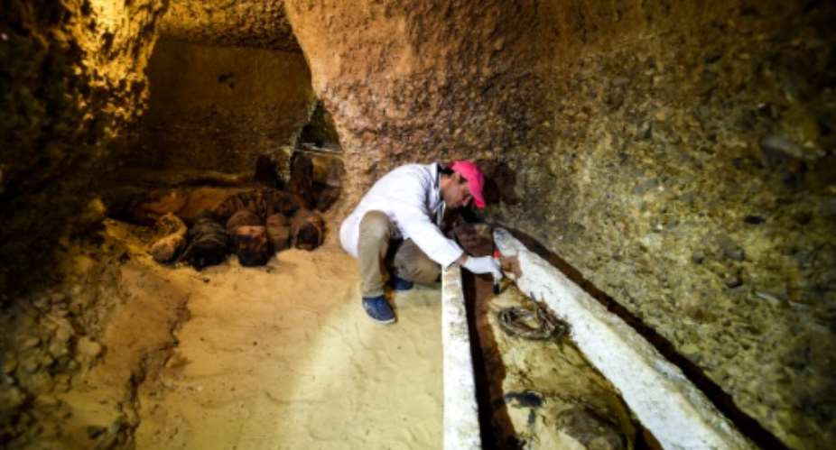An archaeologist brushes a newly-discovered mummy laid inside a sarcophagus, part of a collection found in burial chambers dating to the Ptolemaic era 323-30 BC in February 2019.  By MOHAMED EL-SHAHED AFPFile