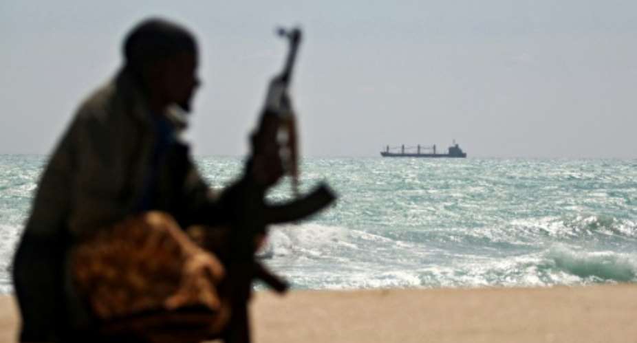 An armed Somali watches a Greek cargo ship anchored off NE Somalia in 2010.  By MOHAMED DAHIR (AFP)