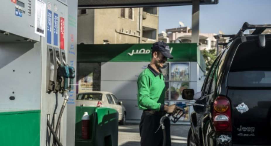 An Egyptian worker fills a customers tank as cars queue at a petrol station in the capital Cairo on November 4, 2016.  By KHALED DESOUKI AFPFile