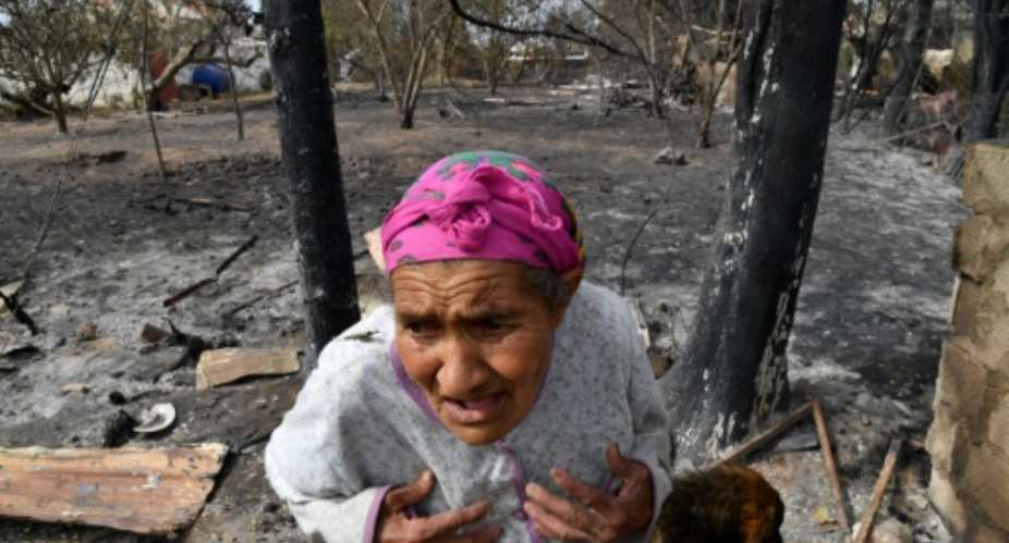 An elderly Algerian woman outside her home, destroyed in a wildfire in the city of el-Kala in August last year.  By - AFPFile