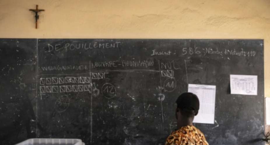 An electoral official views early results during counting at a polling station in Porto-Novo.  By OLYMPIA DE MAISMONT (AFP)
