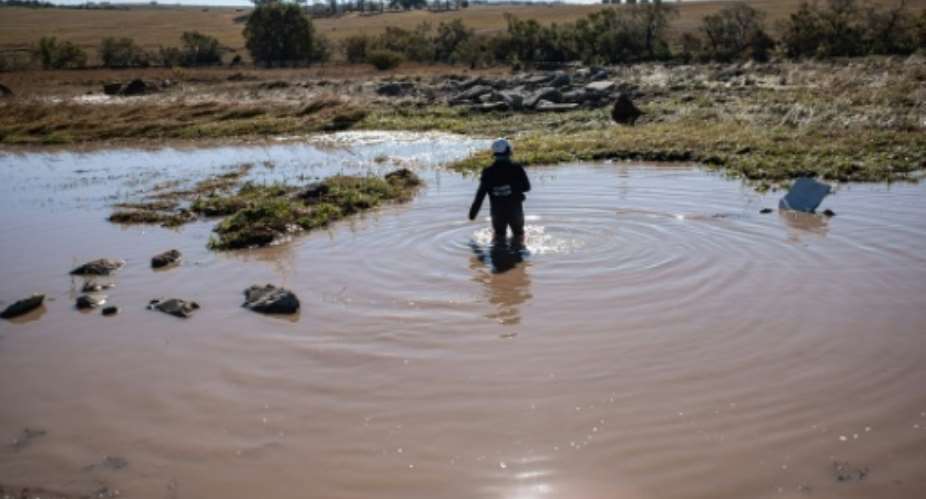 An emergency worker searches for bodies in a pond after deadly floods in South Africas Eastern Cape province.  By EMMANUEL CROSET (AFP)