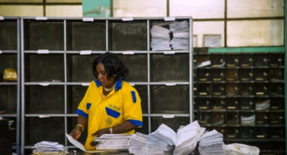 An employee distributes letters and other mail at a branch of the Congolese Company for Posts and Telecommunications in Kinshasa.  By JUNIOR KANNAH (AFP)