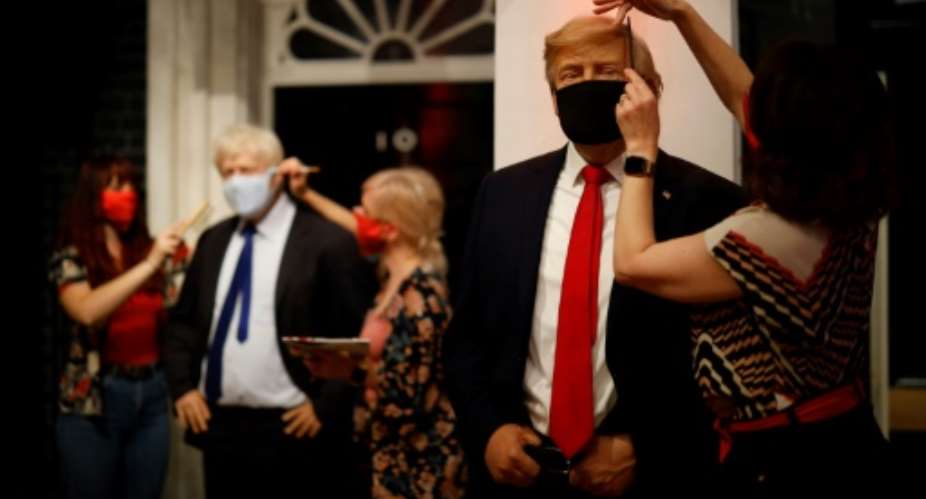 Artists at London's Madame Tussauds check the masks on the wax figures of British PM Boris Johnson and US President Donald Trump.  By Tolga Akmen AFP
