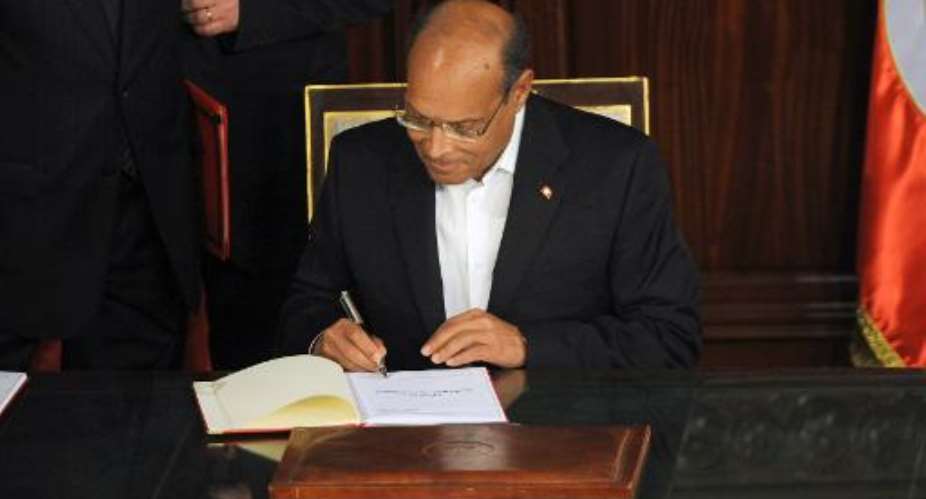 Tunisian president Moncef Marzouki signs a copy of the new constitution after its adoption on January 27, 2014 in Tunis.  By Fethi Belaid (AFP/File)