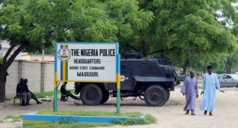 People walk past police armoured tank stationed at the main gate of the state police command headquaters in Maiduguri, Borno State.  By Pius Utomi Ekpei AFPFile