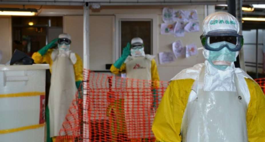 Health workers wearing protective gear gesture at the Nongo ebola treatment centre in Conakry, Guinea, on August 21, 2015.  By Cellou Binani (AFP/File)